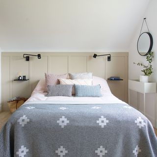 Double bed in front of panelled wall with slimline floating bedside tables and wall lights