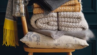 Chair loaded with blankets to show how to keep your house warm in winter
