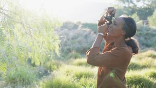 Woman taking a photograph of a tree with a film camera