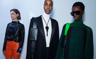 Models wear turtlenecks in white and green, with black leather jackets and blazers. All hold small leather accessories in bright colours