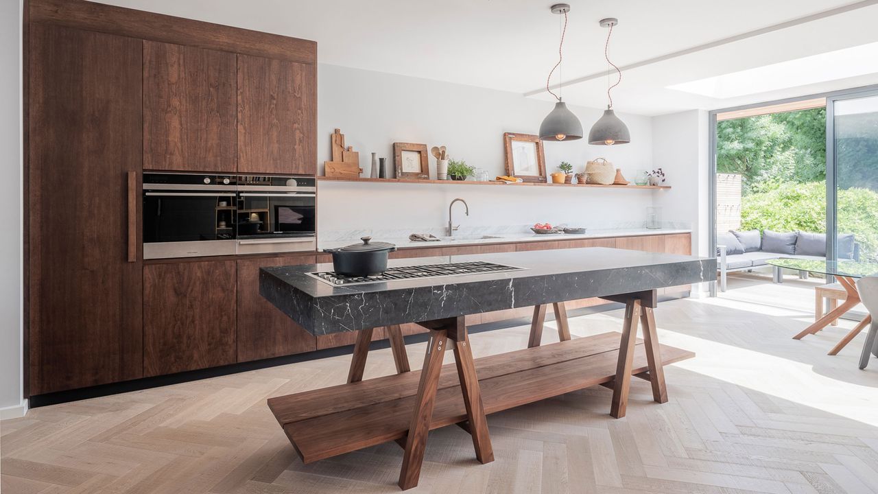 a modern dark wood kitchen with freestanding island with marble slab and open shelving by Naked Kitchens