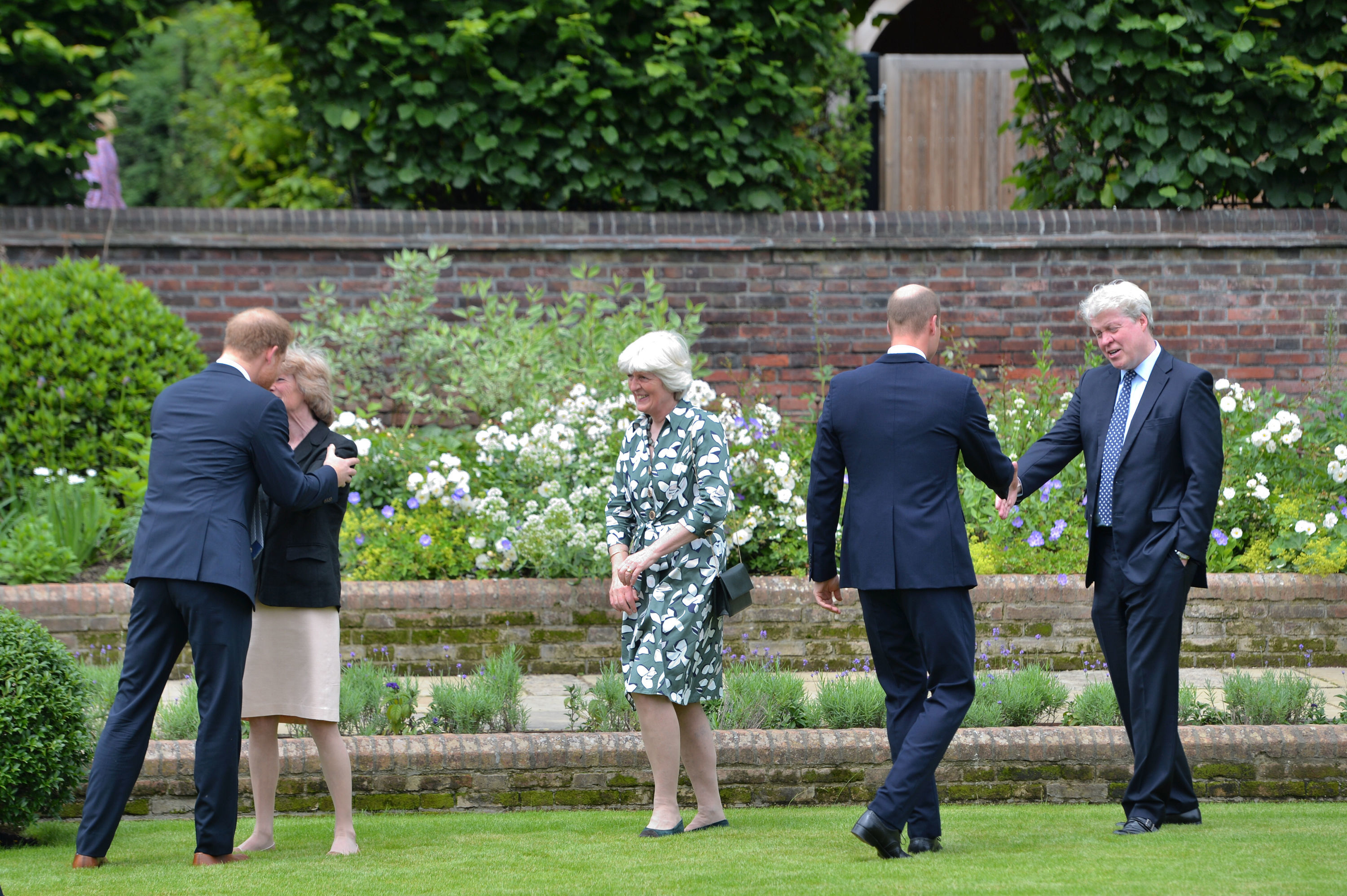 Prince Harry kissing his aunt Lady Sarah, while Prince William shakes Earl Spencer's hand