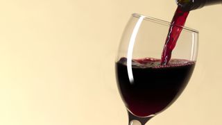 Glass of red wine being poured from bottle