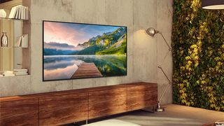 Product image of the Samsung AU8000 TV mounted on a wall in a bright living room