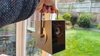 LG CineBeam Q ultra portable projector held in hand in front of garden window