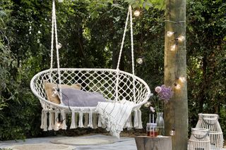 White garden swing seat surrounded by festoon lights