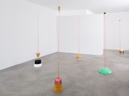 Floor sculptures with long thin poles rising upwards