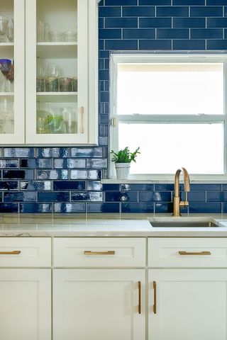 Kitchen with white white cabinets and blue subway tile backsplash