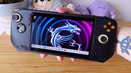 Hand holding MSI Claw A1M handheld with Windows 11 on screen.
