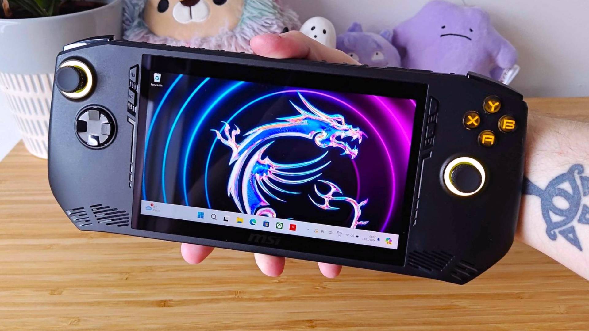 Hand holding MSI Claw A1M handheld with Windows 11 on screen.