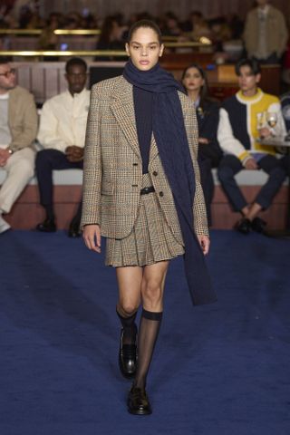 Tommy Hilfiger model wearing plaid blazer and matching skirt with sheer socks and loafers
