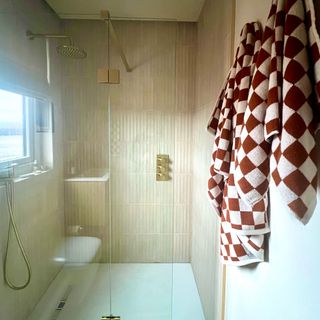 small shower room with brass shower and check towels