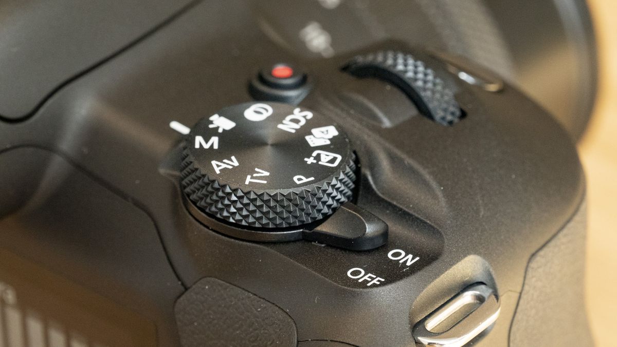 Canon EOS R100 camera on a table closeup of shooting mode dial