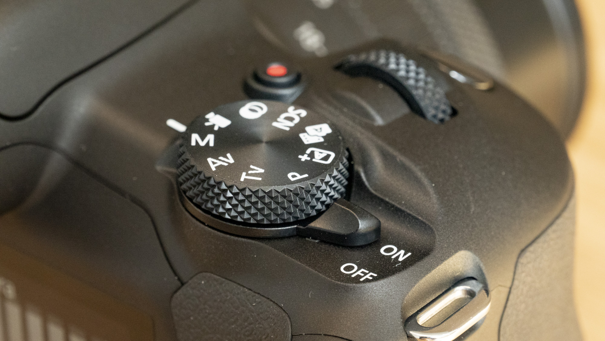 Canon EOS R100 camera on a table closeup of shooting mode dial