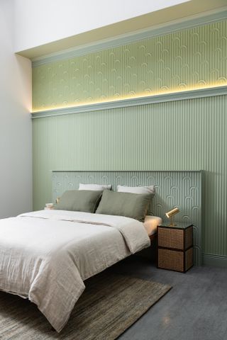 a green bedroom with lighting in the wall moldings