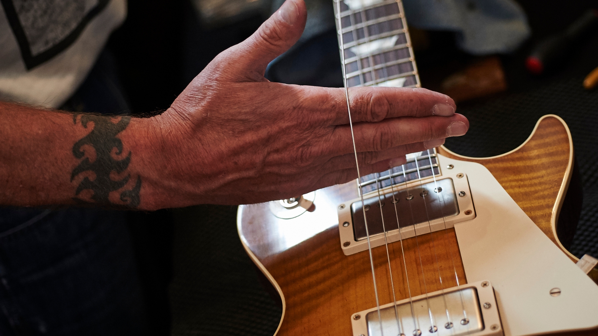 A man stretches an electric guitar string on a Les Paul guitar