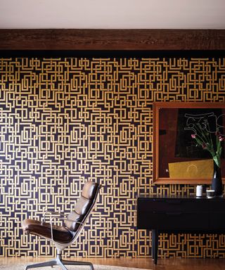 Metallic, geometric wallpaper with leather retro chair and black lacquer dresser