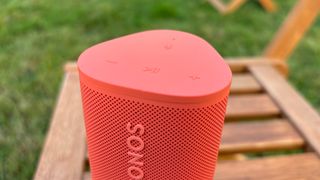 Sonos Roam 2 wireless speaker stood on end on wooden bench showing controls