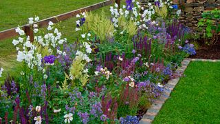 Small garden border in cottage garden edged with bricks