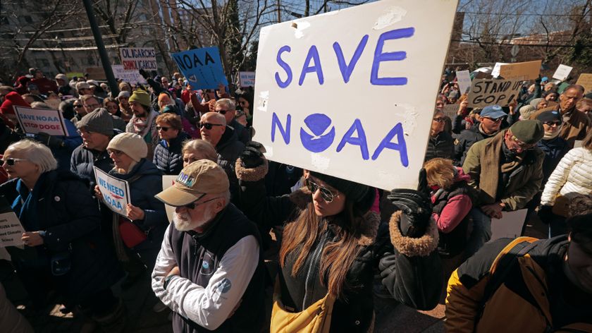 A person at a crowded protest holds a sign that says SAVE NOAA