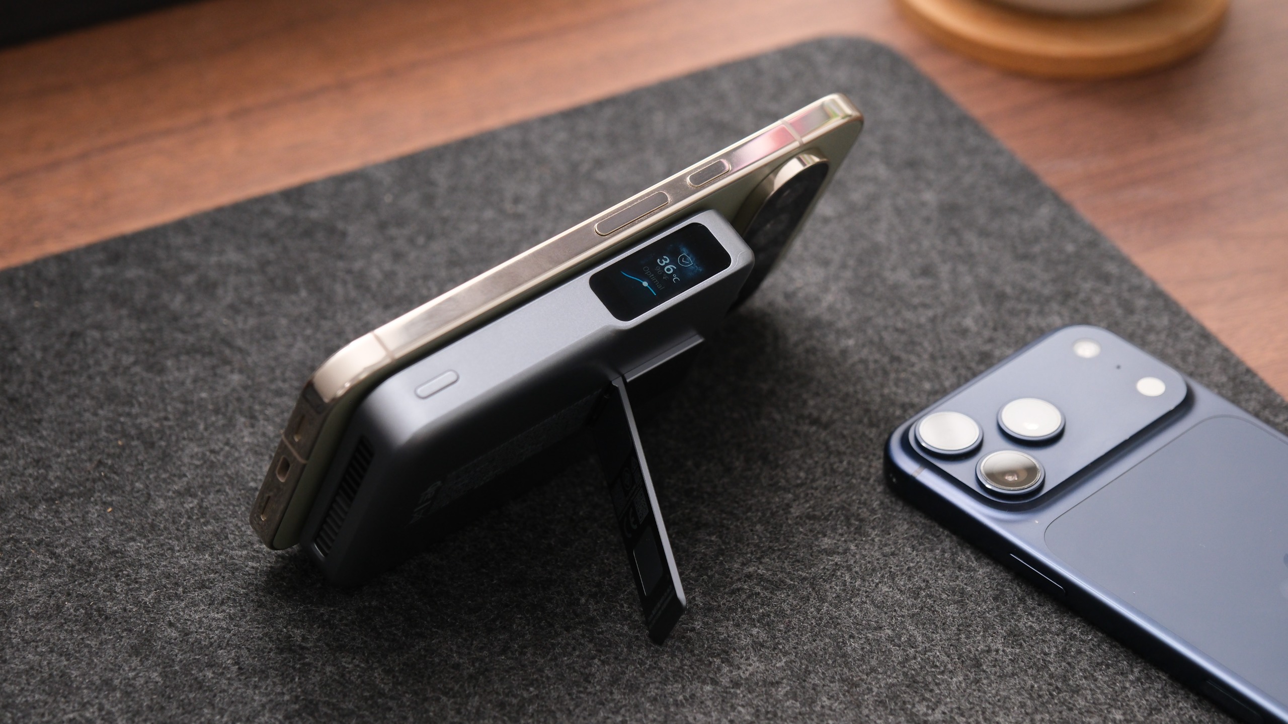 Anker MagGo Power Bank 2 Pro attached magnetically to a smartphone and propped up using its built-in kickstand, with another phone lying alongside.