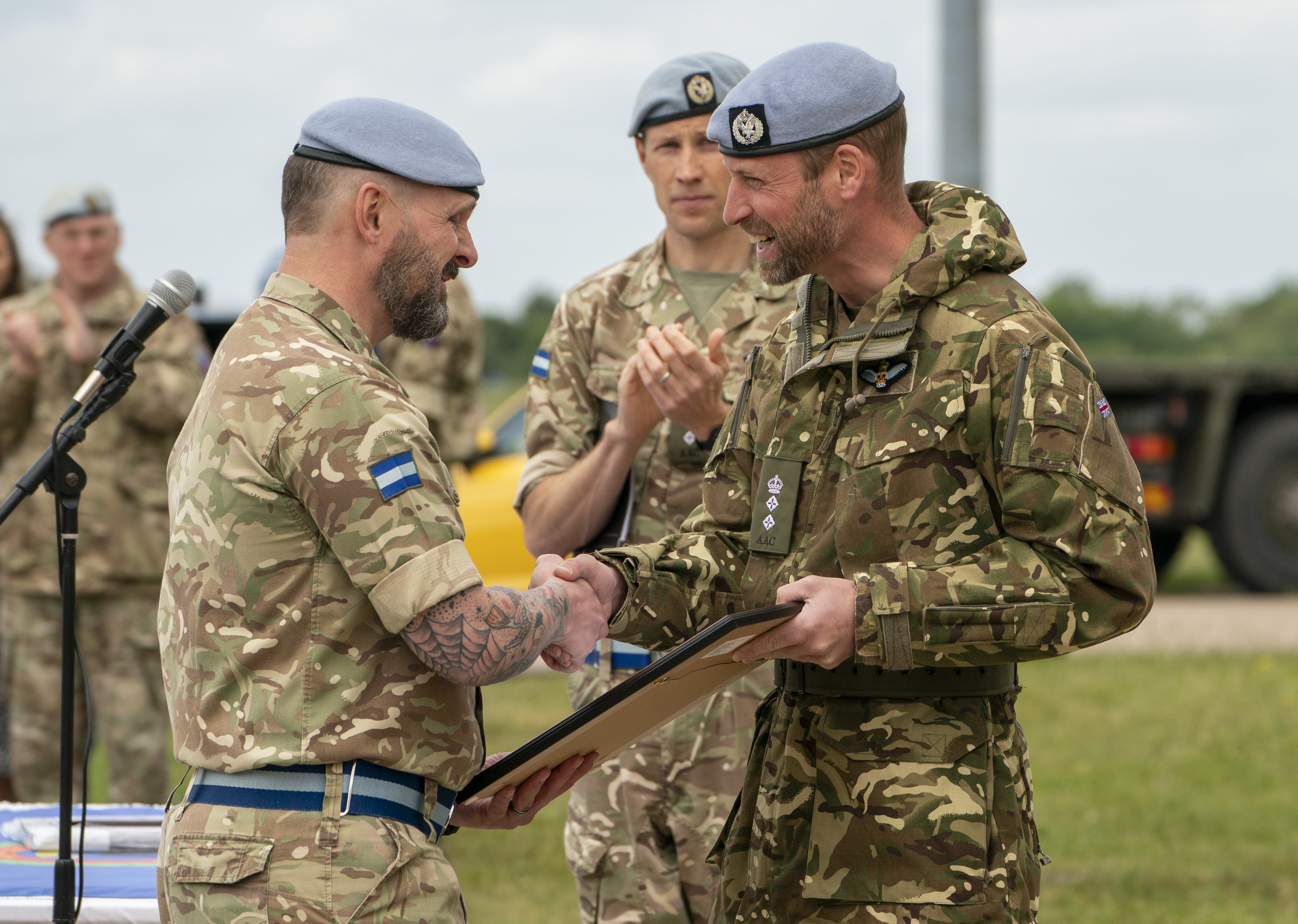 Prince William wearing a military uniform shaking hands with a soldier