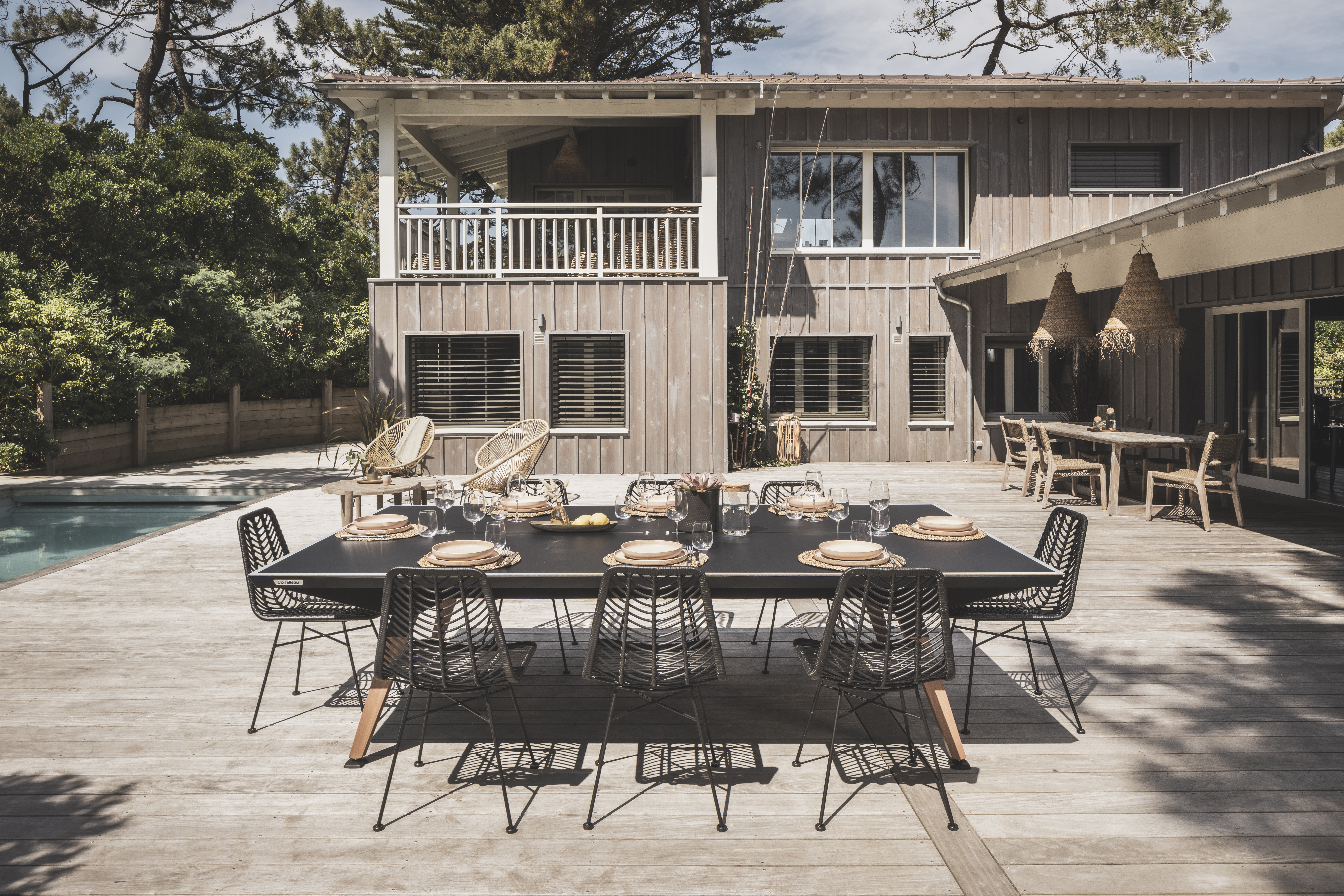 an image of a luxury Cornilleau tennis table, wihtout the net, set up to look like an outdoor dining table on the patio of a luxury house