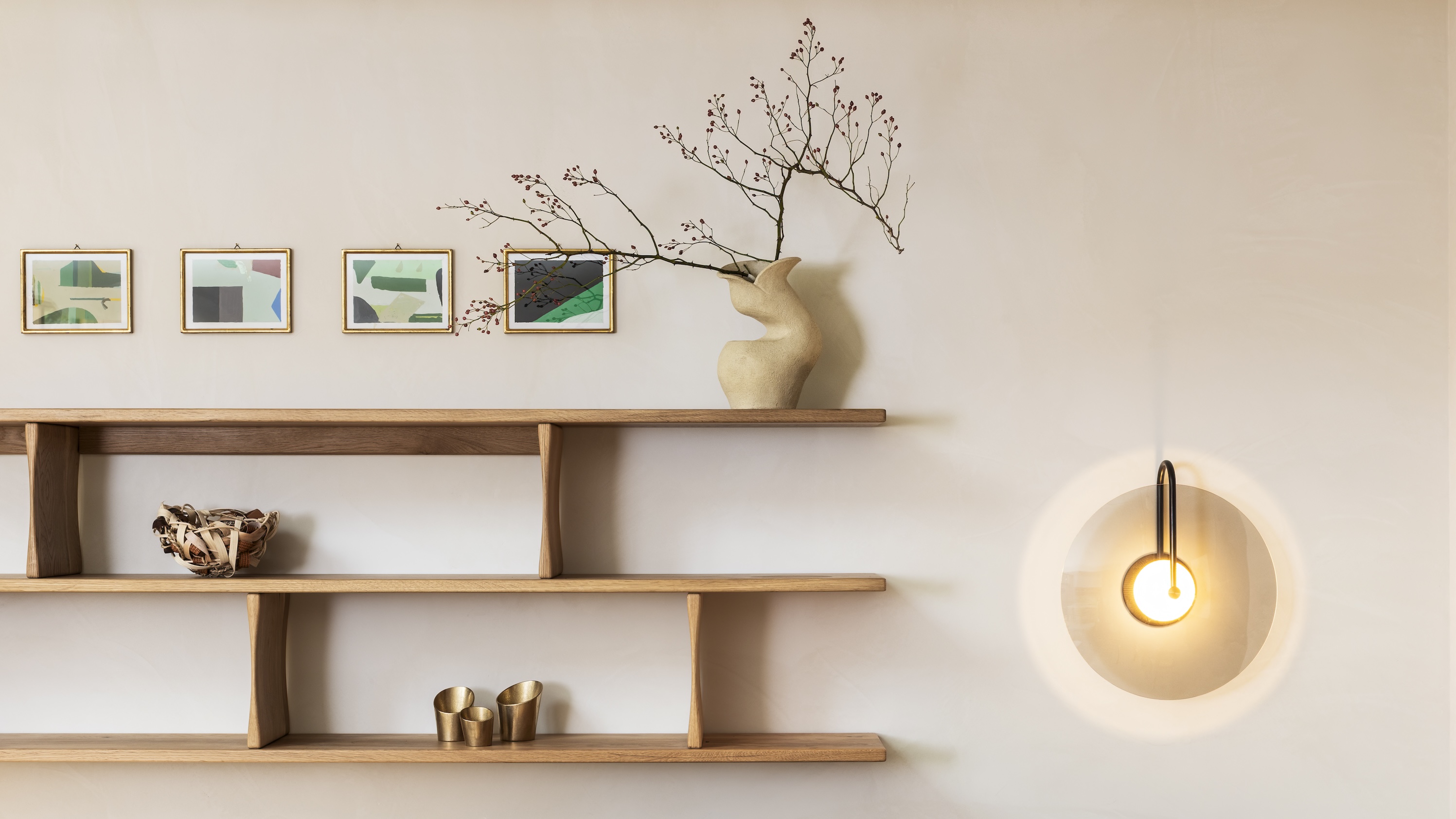 A shelving system with small pieces of decor next to a wall sconce