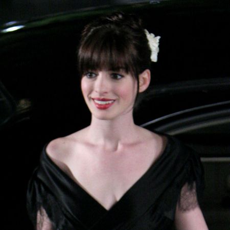 Anne Hathaway wearing a black dress with red lipstick as she films The Devil Wears Prada in 2005