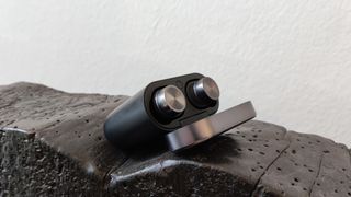 The Bowers & Wilkins Pi7 S2 true wireless earbuds in their charging case against a wooden surface.