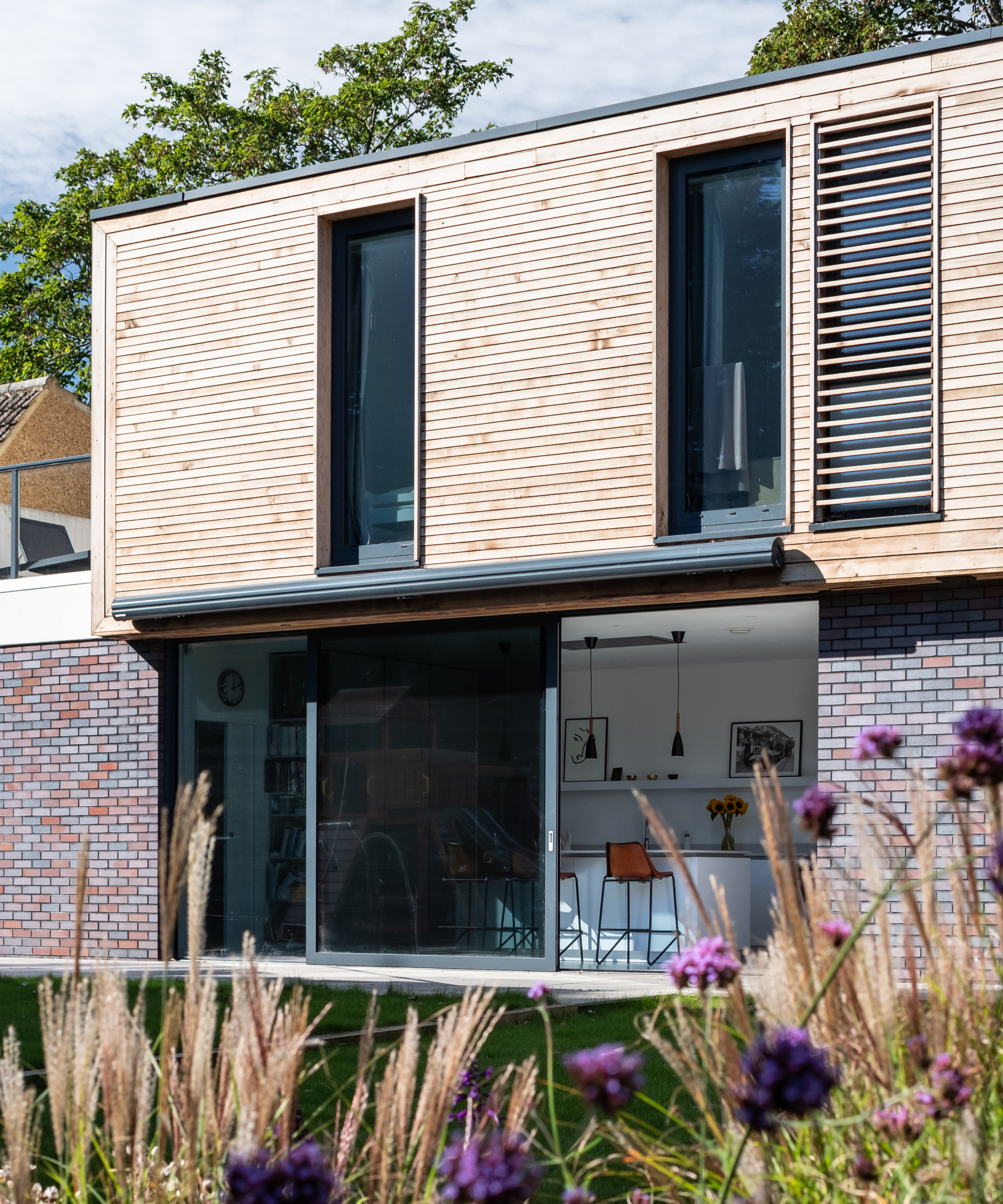 modern two-storey self build with timber cladding on second floor, brick on first floor and large sliding patio doors