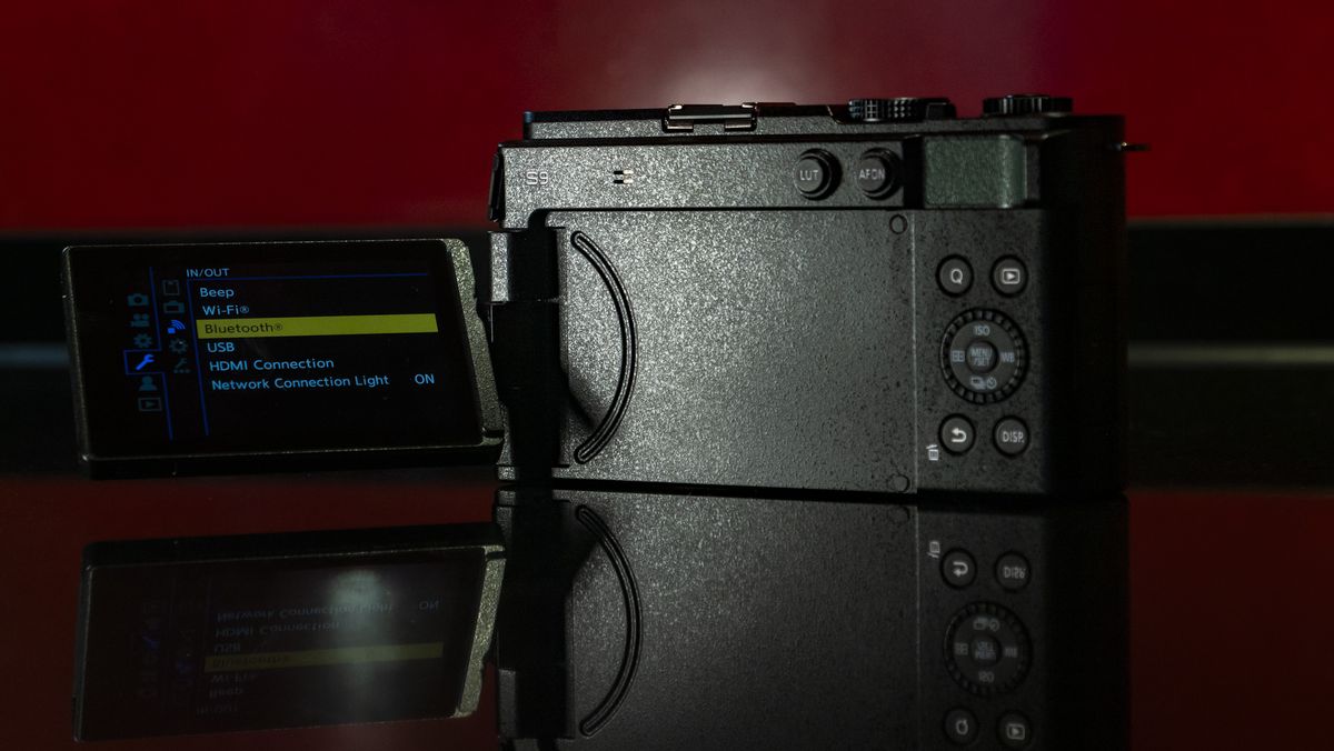 Panasonic Lumix S9 camera in Dark Olive color on a rich red reflective surface