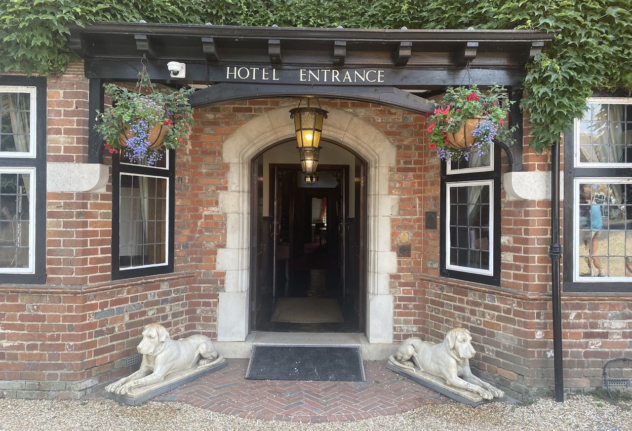 The entrance to the dog-friendly hotel The Montagu Arms with an ancient wooden door flanked by two dog statues