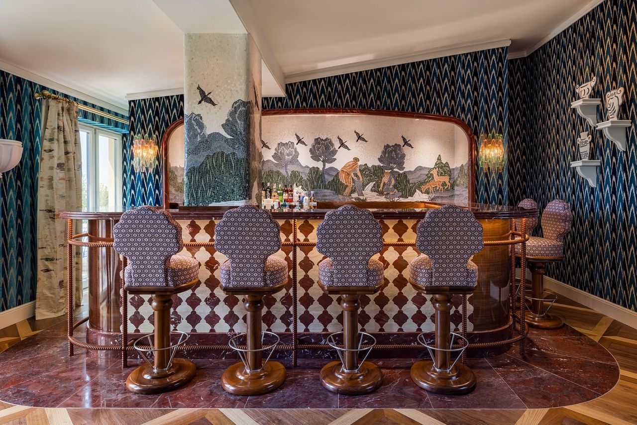 An eccentrically decorated hotel bar features Roman mythology-inspired wall mosaics.
