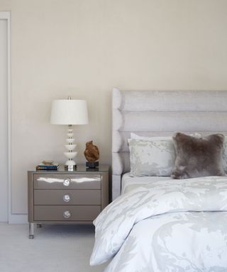 neutral bedroom with upholstered headboard and taupe bedside chest