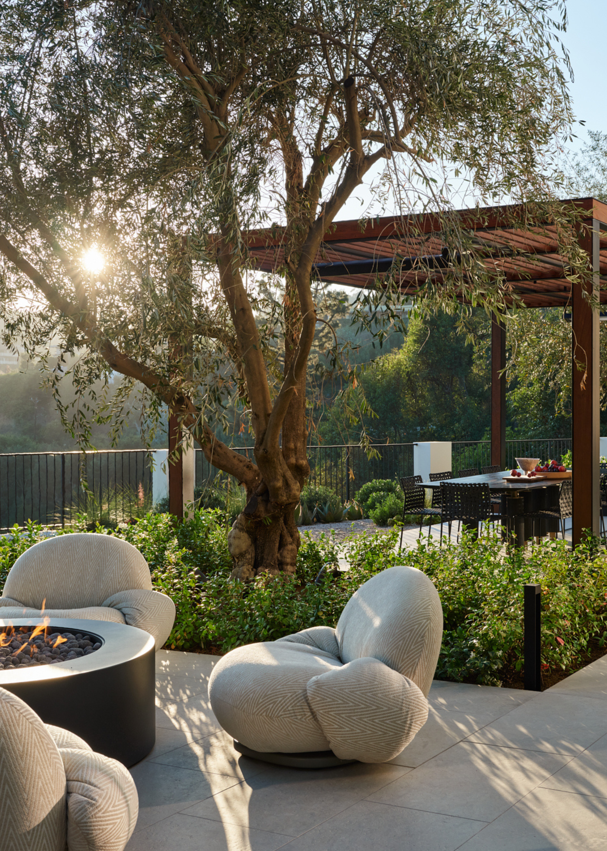 A terrace garden with a round firepit, a set of garden chairs, and plants