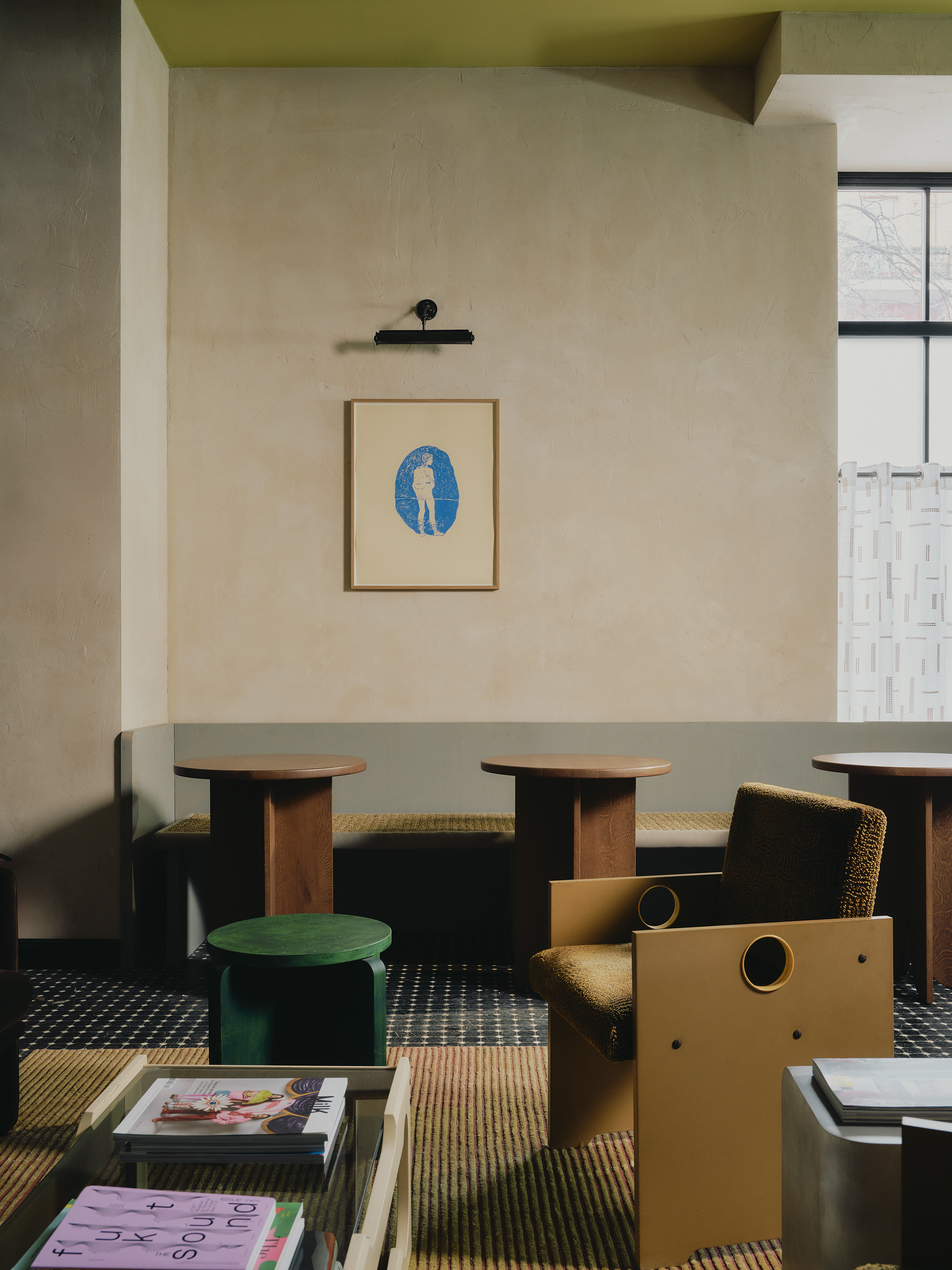 Interiors of a colorfully decorated hotel with a green, pink, and red palette, checkered or striped flooring, quirky, sculptural collectibles throughout, and lots of natural light.