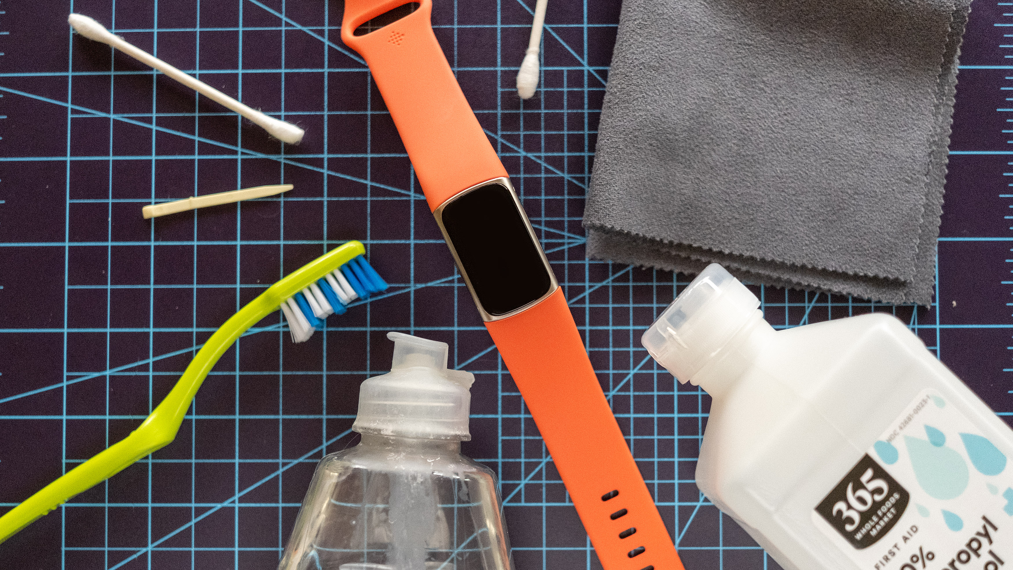يظهر جهاز Fitbit Charge 6 بجوار أدوات التنظيف بما في ذلك فرشاة الأسنان والكحول المحمر.