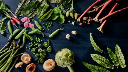 Overhead view of fresh spring vegetables sitting on a black background