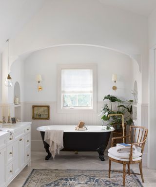 bathroom with roll top and vintage rug and arched wall