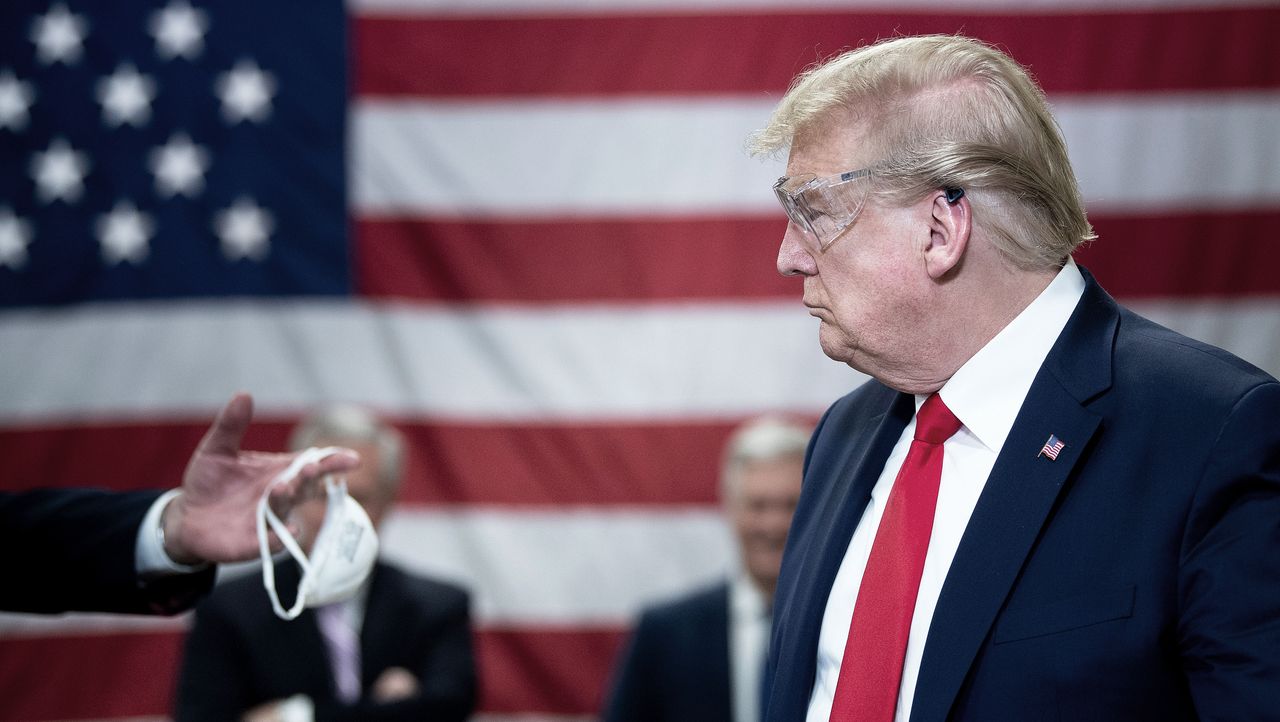 Donald Trump is handed a mask during a factory visit