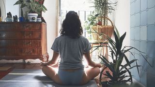 woman practicing yoga at home with back turned