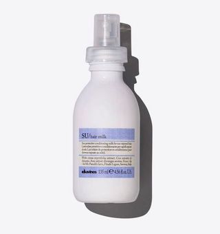 SU hair milk by Davines in white spray bottle against grey background