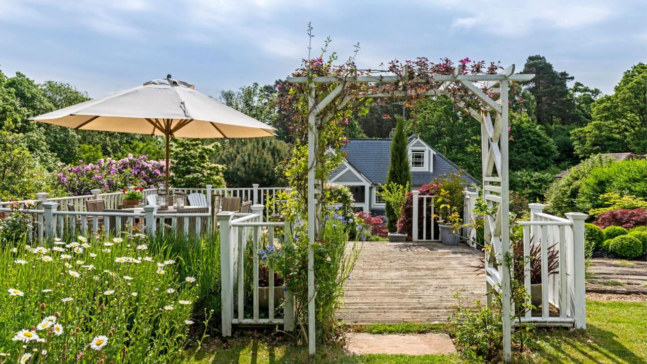  Garden terrace with sun umbrella. New England Style renovation. A renovated and extended1920s country house in the New England style, in Surrey, England, home of JP Clark and husband