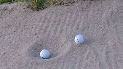 Two golf balls pictured in a bunker