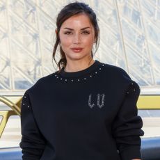 Ana de Armas celebrates the 130th anniversary of Louis Vuitton's monogram in a polo sweater, bootcut jeans, and two Louis Vuitton bags