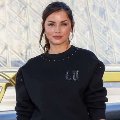 Ana de Armas celebrates the 130th anniversary of Louis Vuitton's monogram in a polo sweater, bootcut jeans, and two Louis Vuitton bags