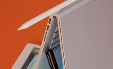 tablet lying flat with the screen on, a grey tablet cover folder over standing, a white, black and rose gold stylus's 