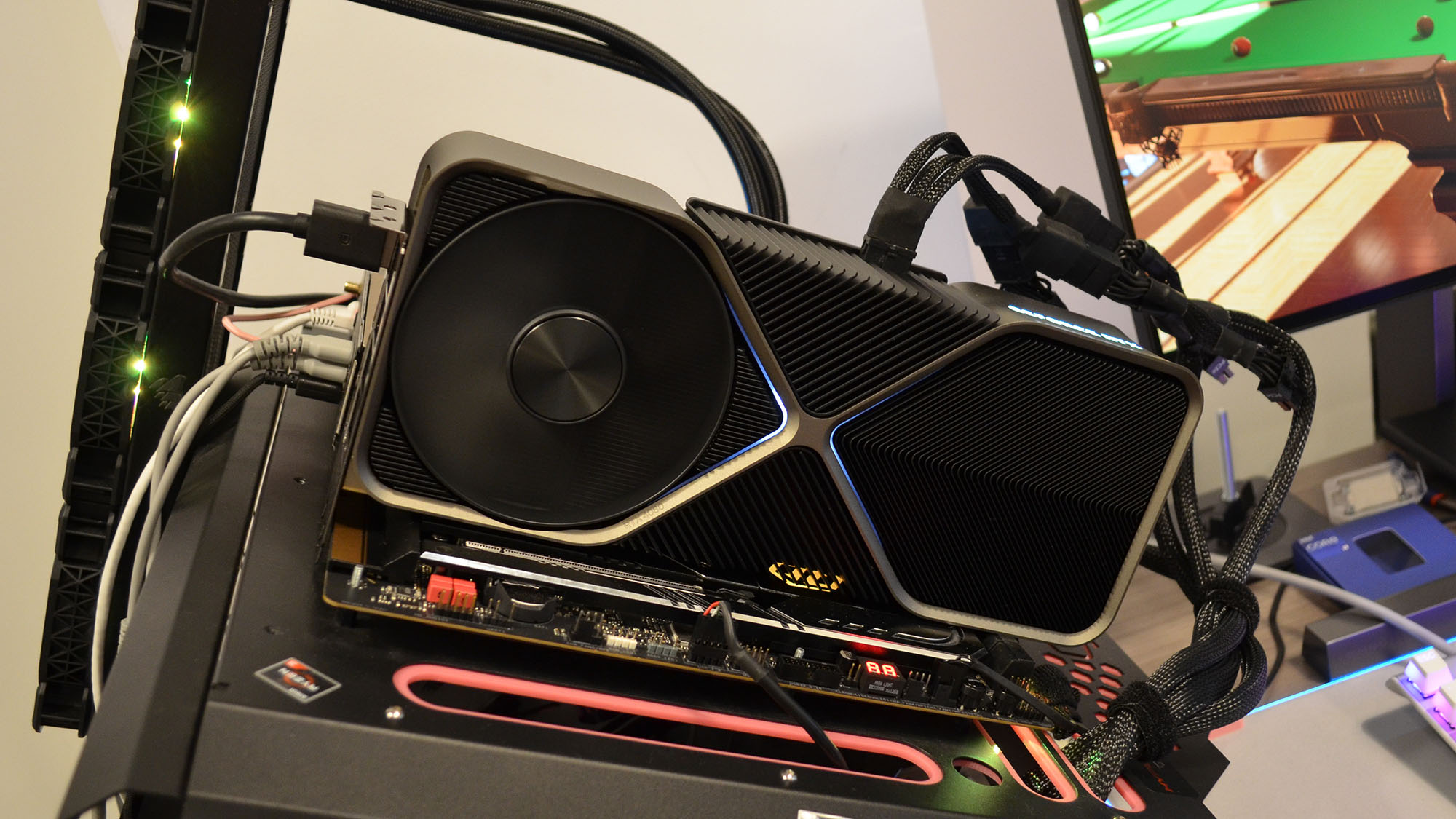 Une Nvidia GeForce RTX 4080 sur un bureau en bois devant un panneau blanc.