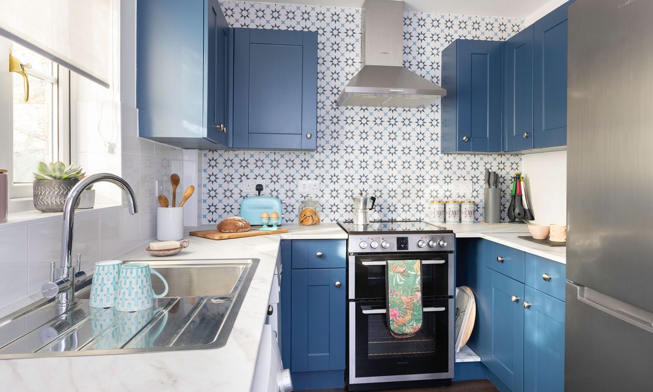 Blue kitchen cabinets with geometric tiles, stainless steel sink and tap, wooden flooring